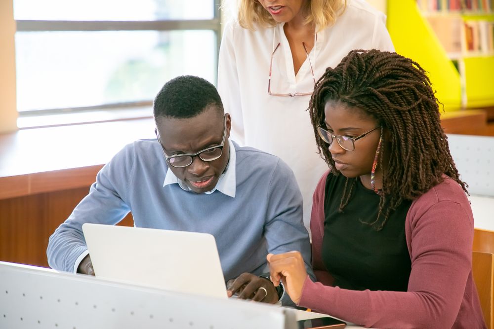 A counsellor guiding two Nigerian students through their options at a laptop
